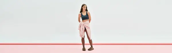 A young beautiful woman poses in a chic outfit, radiating confidence within a modern setting. — Stock Photo