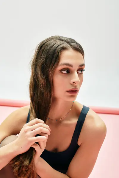 A young and beautiful woman gently touches her hair, lost in thought against a soft backdrop. — Stock Photo