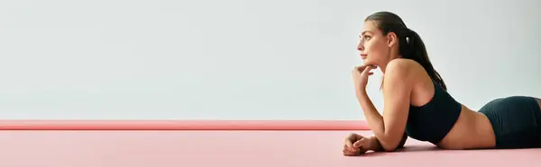 A young woman relaxes on a pink mat, lost in thought in a peaceful space. — Stock Photo