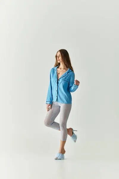 A young woman models a stylish blue outfit with a graceful, relaxed stance. — Stock Photo