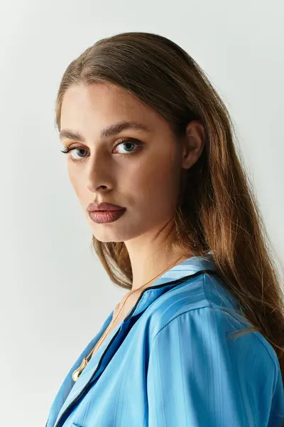 A confident young woman in a trendy blue outfit shows off her beauty with long hair. — Stock Photo