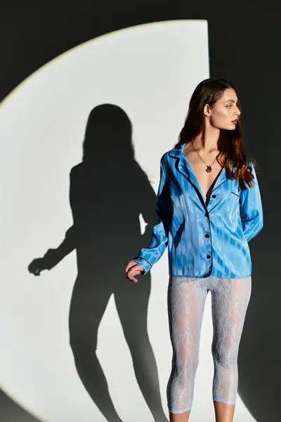 Beautiful young woman stands gracefully, casting a long shadow on abstract background. — Stock Photo