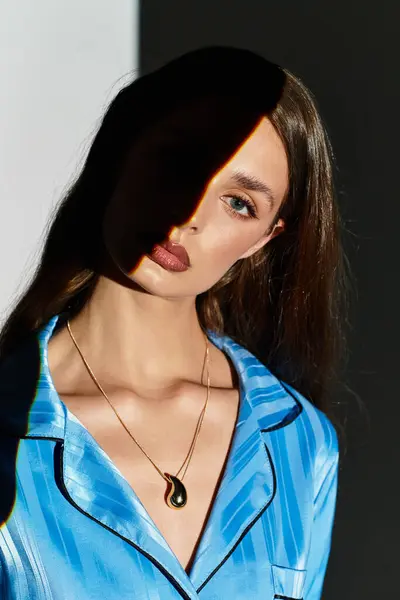 A young, graceful woman poses against a backdrop of light and shadow, radiating elegance. — Stock Photo
