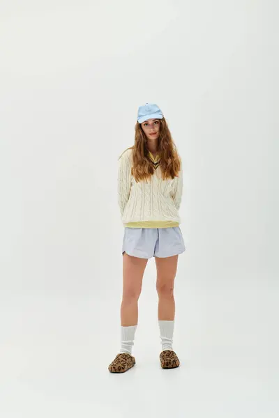 Eine junge Frau steht mit den Händen hinter dem Rücken in einem trendigen, lässigen Outfit. — Stockfoto