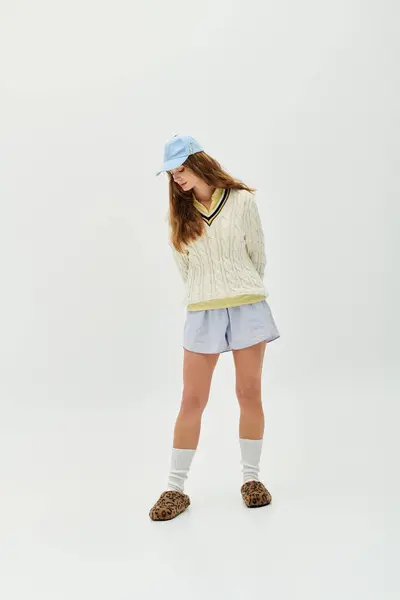 Eine selbstbewusste junge Frau in stylischem Pullover und kurzer Hose posiert mit lustigen Accessoires. — Stockfoto