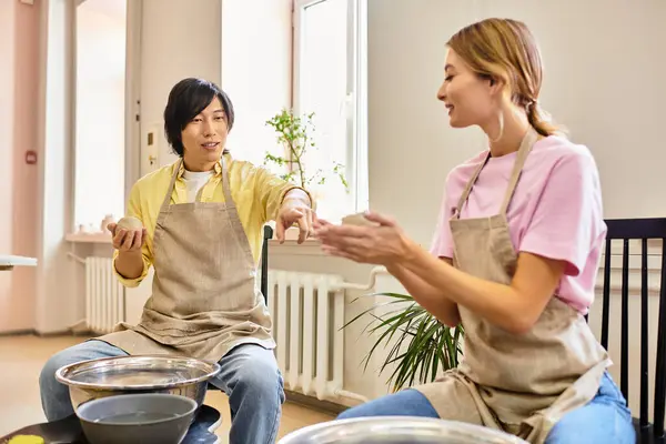 A young couple joyfully creates pottery together in a vibrant art studio. — Stock Photo