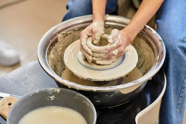 Hands shape clay on a potters wheel in a bright, welcoming pottery studio. — Stock Photo