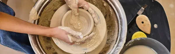 Hands shape clay into a bowl amidst tools and artistic inspiration. — Stock Photo