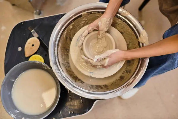 Skilled hands mold clay on a pottery wheel in a bright, creative studio. — Stock Photo