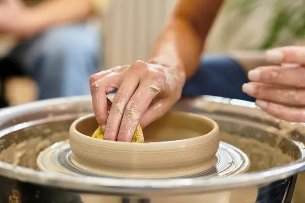 Hands expertly shape pottery with a sponge in a bright studio. — Stock Photo