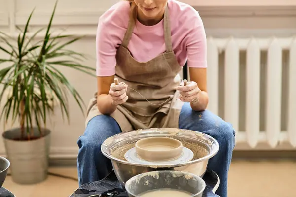 An artisan diligently shapes a beautiful pottery piece on a wheel in a bright studio. — Stock Photo