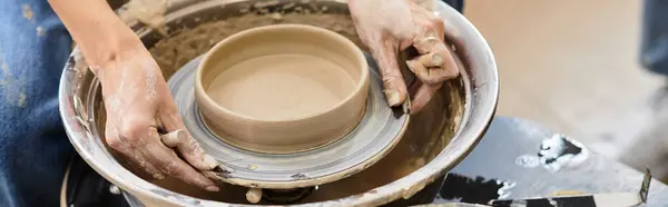 Artisan shapes clay into a stunning bowl, surrounded by colorful pottery tools and vibrant decor. — Stock Photo