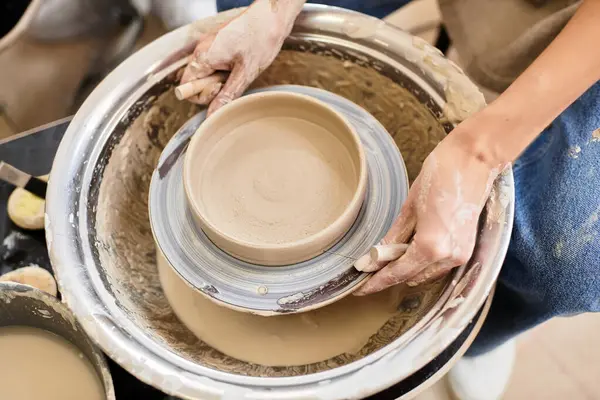Hands skillfully shape clay into a stunning bowl on a potters wheel in a lively studio. — Stock Photo