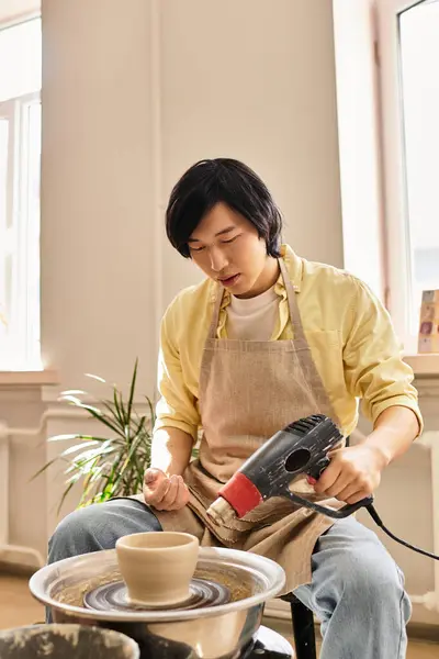 A young artist focuses on crafting pottery using a wheel in a bright and inviting studio space. — Stock Photo