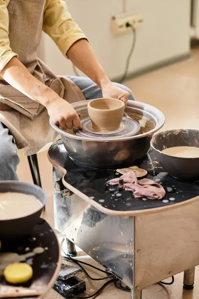 Hands expertly shape clay into a bowl on a pottery wheel in a bright and inviting workspace. — Stock Photo