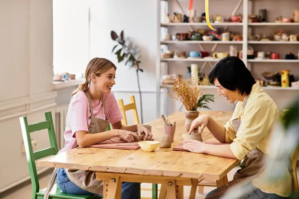 A young couple joyfully molds clay in a bright, art filled pottery studio. — Stock Photo