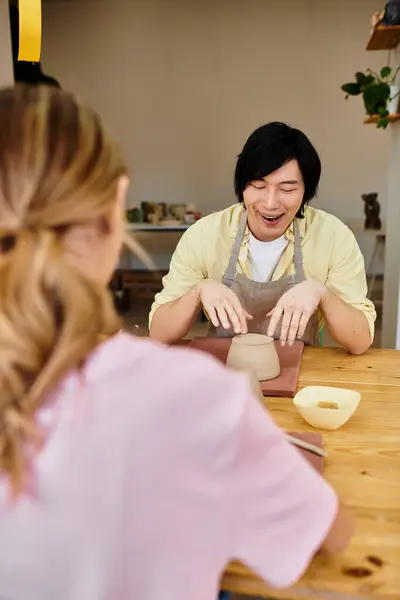 A young couple engages in pottery making, laughing and enjoying the creative process together. — Stock Photo