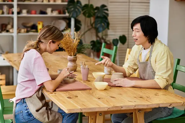 Young couple enjoys a creative pottery session in a welcoming art studio filled with natural light. — Stock Photo