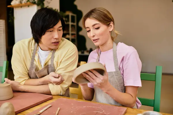 A young couple shares smiles while molding clay in a cozy pottery studio. — Stock Photo