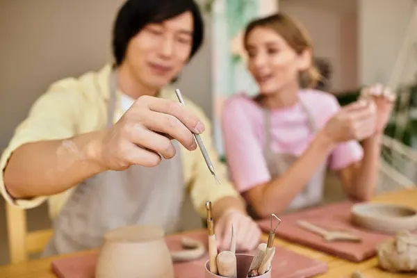 In a bright pottery studio, a couple laughs as they create unique clay pieces together. — Stock Photo