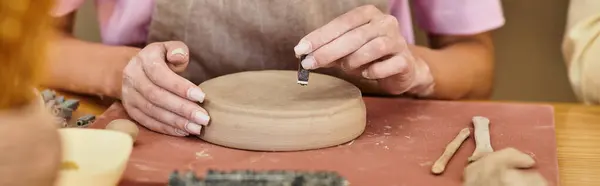 Artisan shapes clay with care amid the lively atmosphere of a pottery studio. — Stock Photo