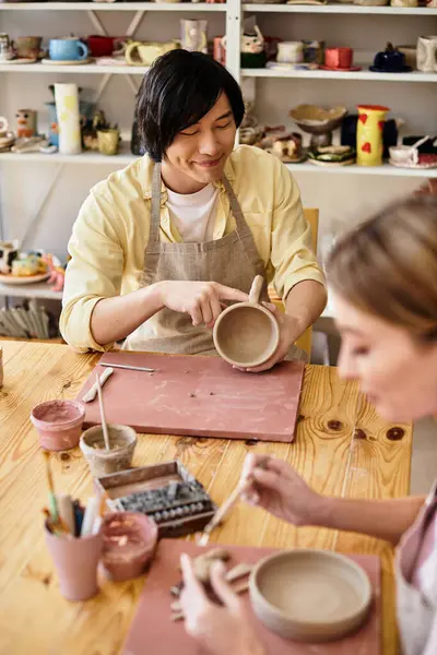Young couple enjoys crafting pottery in a charming studio, sharing laughter and creativity. — Stock Photo