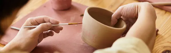 Hands skillfully mold and paint clay into beautiful pottery creations in a bright studio. — Stock Photo