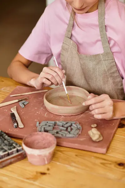 A dedicated artist brings life to clay with careful brush strokes in a lively pottery studio. — Stock Photo