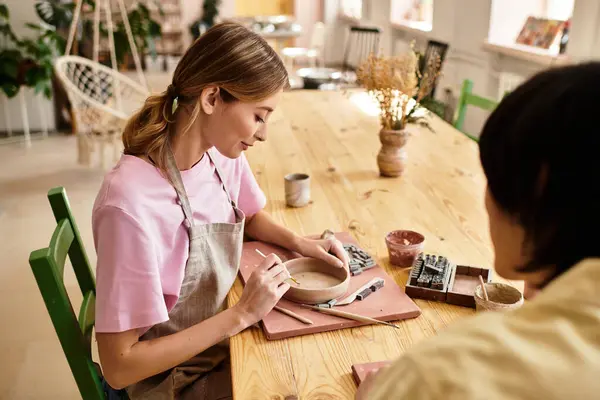 A young couple joyfully molds clay together in a pottery studio, immersed in creativity. — Stock Photo