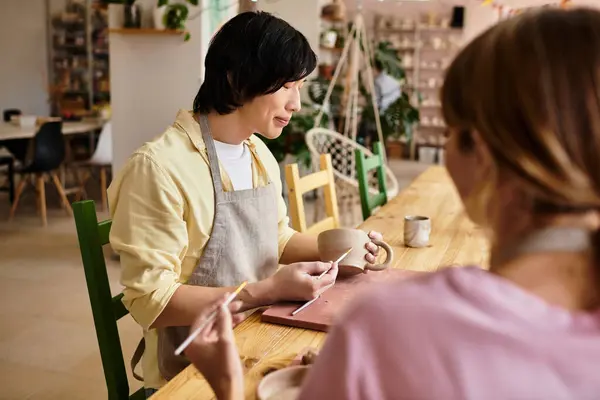 Pareja joven disfruta de la elaboración de cerámica en un estudio de arte, profundizando su vínculo a través de la creatividad. - foto de stock