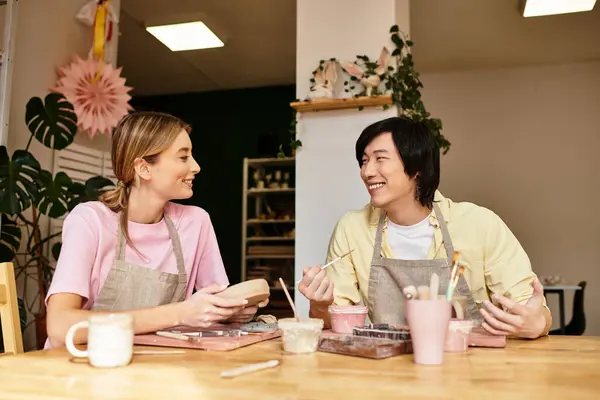 Una giovane coppia si gode una sessione di ceramiche giocose mentre si scambiano sorrisi e idee artistiche insieme — Foto stock
