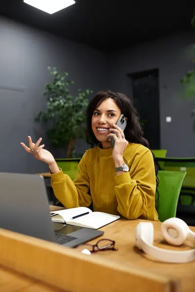 Eine elegant gekleidete junge Frau telefoniert während ihrer Arbeit an einem stilvollen Schreibtisch. — Stockfoto