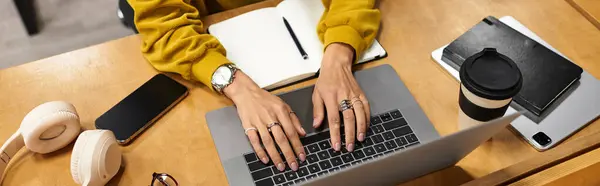 Chic young woman types on a laptop, surrounded by notebooks, coffee, and stylish items. — Stock Photo