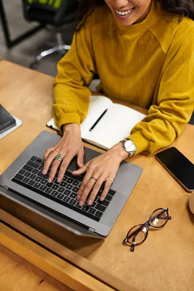A young, beautiful woman in a chic sweater works diligently at her office desk. — Stock Photo