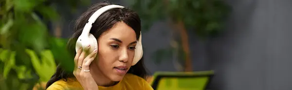 Elegant woman immersed in her tasks, wearing headphones in a bright and modern office environment. — Stock Photo