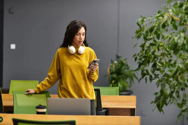 Young, beautiful woman engaged in work activity, focused on her mobile device in an office space. — Stock Photo