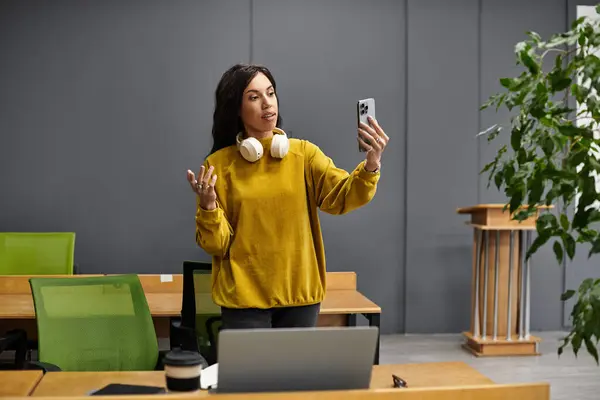 Schöne Frau führt einen Videoanruf durch, während sie in einem eleganten, modernen Büroraum arbeitet. — Stockfoto