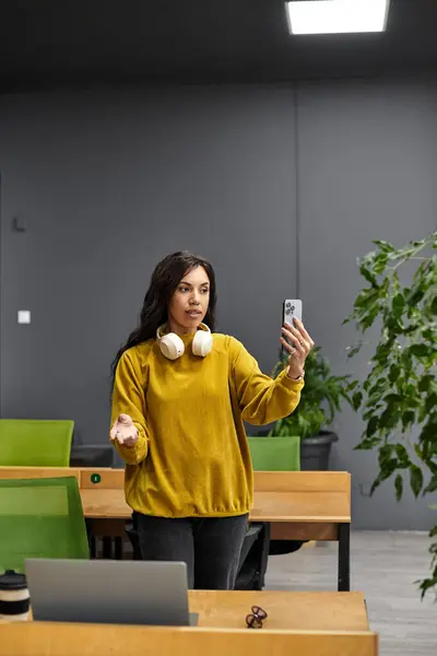 Young woman with stylish headphones is actively participating in a virtual meeting in an office. — Stock Photo