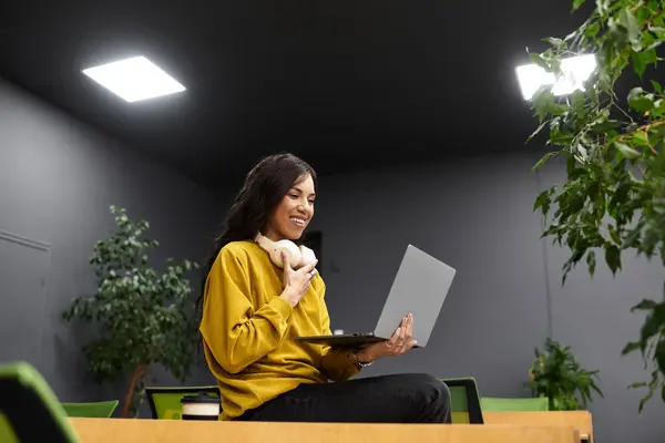 Focused and stylish, a young woman explores new ideas while working on her laptop in a chic office. — Stock Photo