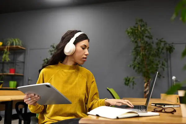 Elegant young professional focused, balancing tasks with a tablet and laptop in a chic office. — Stock Photo