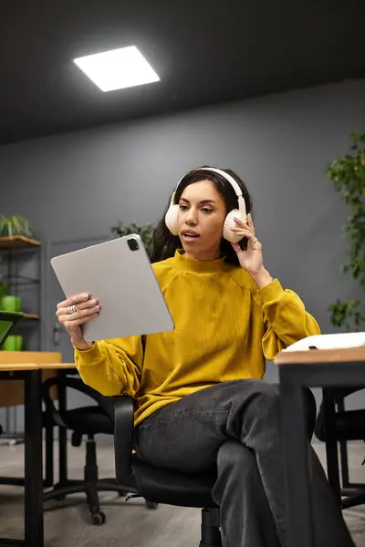 Young and beautiful woman in casual attire using a tablet while seated in a stylish workspace — Stock Photo