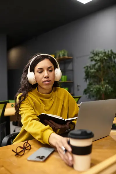 Focalizzata sui suoi compiti, la bella donna in un maglione accogliente si impegna con il suo computer portatile e note. — Foto stock