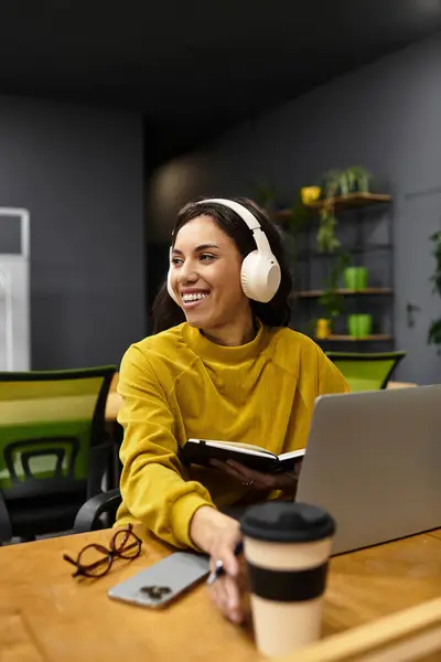 Donna concentrata in un ambiente ufficio moderno lavora diligentemente con il suo computer portatile e caffè. — Foto stock
