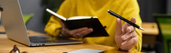 A beautiful and graceful woman focuses on her tasks with a notebook and laptop at her desk. — Stock Photo