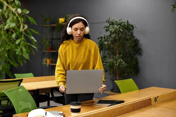 Young woman focuses on her laptop while enjoying a peaceful moment in an elegant office space. — Stock Photo
