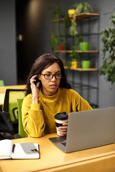 Young professional focused on her tasks in a stylish office, savoring a warm beverage as she works. — Stock Photo