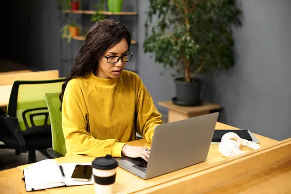 In a modern office, a stylish woman focuses intently on her laptop with professionalism. — Stock Photo