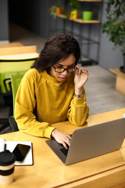 A beautiful, elegant woman is diligently working on her laptop in a modern office environment. — Stock Photo