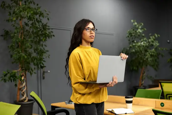 Confident woman in a modern workspace works intently on her laptop. — Stock Photo