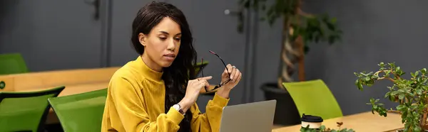 Una joven hermosa y elegante está trabajando intensamente en su computadora portátil en un entorno de oficina moderno. - foto de stock